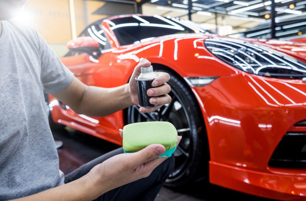 Detailer preparing ceramic coating applicator in front of red sports car in Northern Virginia